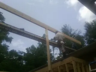 Carpenter setting a ridge beam over a new addition frame — Ice Dam Removal by Roofing Brothers in Linville